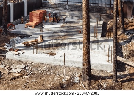 Construction site showcasing a monolithic slab foundation surrounded by trees