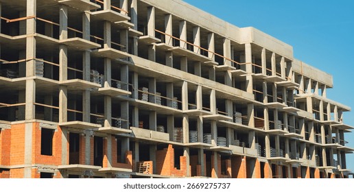 Construction site showcasing progress on a multi-story building under a clear blue sky.