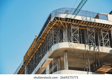 Construction site showcasing progress on a multi-story building under a clear blue sky.