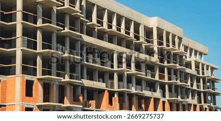 Construction site showcasing progress on a multi-story building under a clear blue sky.