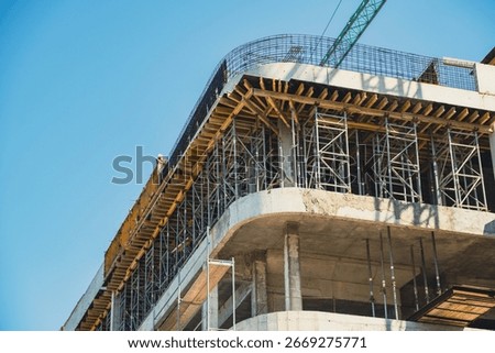 Construction site showcasing progress on a multi-story building under a clear blue sky.