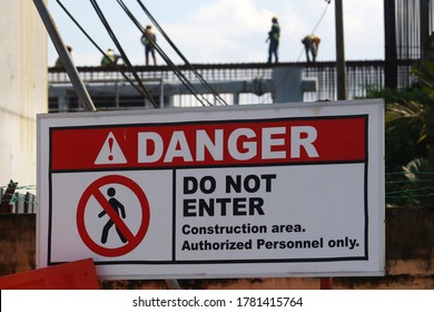 A Construction Site Sign Is Tagged To A Green Mesh Tarp That's Covered In Graffiti. The Sign Warns Passerby's Trespassing Is Not Allowed And The Site Is Dangerous.