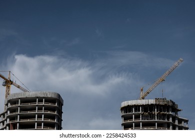 construction site with two tower cranes on a blue sky background. - Shutterstock ID 2258424533