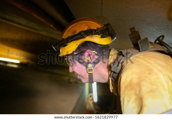 Construction site worker wearing yellow  safety hard hat\
fall protection clear glass ear plug while working in confined\
space noisy areas 