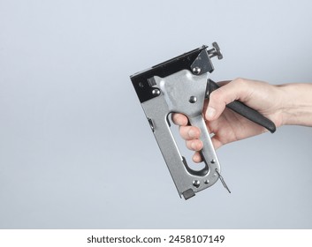 Construction stapler in hand on gray background