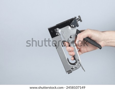 Construction stapler in hand on gray background
