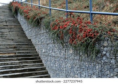 construction of a steep staircase by the stone wall car park with high durability even under heavy load galvanized steel floor grate and railings. gabion above him a wire fence. corridor, narrow - Shutterstock ID 2277237945