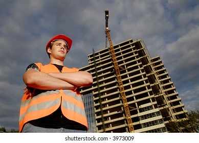 Construction Supervisor In Safety Helmet And Reflex Vest In Front Of Construction Site.