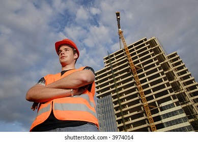 Construction Supervisor In Safety Helmet And Reflex Vest In Front Of Construction Site.