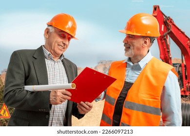 Construction supervisor, workers at a construction site. Managers wearing protective workwear, hard hat looking at clipboard, excavator, bulldozer. Construction workforce, working labor man.