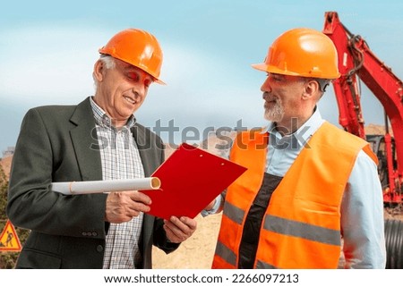 Construction supervisor, workers at a construction site. Managers wearing protective workwear, hard hat looking at clipboard, excavator, bulldozer. Construction workforce, working labor man.