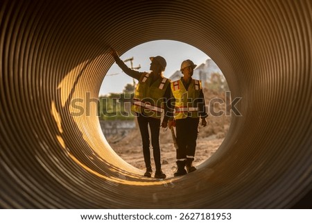 Construction surveyor or engineer working in pipe construction site for inspection detail of construction with heavy machinery excavator constructed hi-way road background.