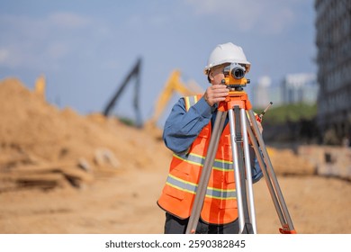 Construction surveyor or engineer working construction site to theodolite mounted  tripod for measuring angles and distances with heavy machinery excavator constructed hi-way road background.