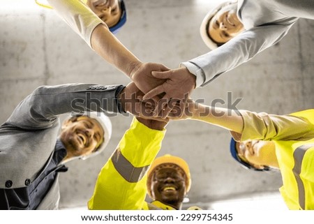 Construction teamwork. Workers, engineers and architects holding hands together in the building.
