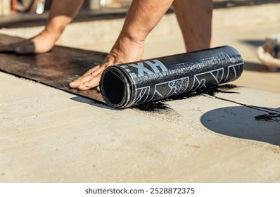 Construction techniques for waterproofing basement and foundations. Insulation material on the basement concrete wall. Waterproofing house foundation with spray on tar and roll waterproofing