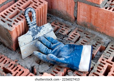 Construction tool for laying bricks and blocks. Bricklayer's tools - hammer, spatula, trowel, gloves. Hand tools on the background of brickwork - Shutterstock ID 2236027413