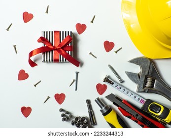Construction tools and gift on white background with small red hearts and copy space. Construction greeting card for Valentines day. Repair home with love. Gifts for lover. Buying presents for man.