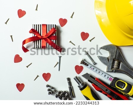Construction tools and gift on white background with small red hearts and copy space. Construction greeting card for Valentines day. Repair home with love. Gifts for lover. Buying presents for man.