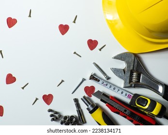 Construction tools, hard hat on white background with small red hearts and copy space. Construction greeting card for Valentines day. Repair home with love. Gifts for lover. Buying presents for man.