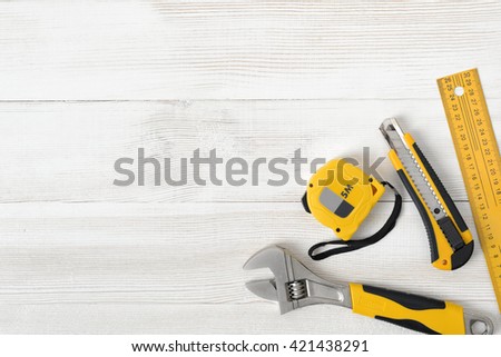 Construction tools including centimeter ruler, wrench and cutter placed in the right down corner on wooden surface with open space. Top view composition. Measurement. Fixing and cropping. Hand tool