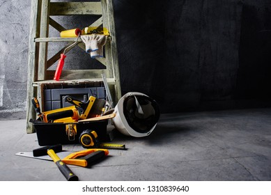 Construction tools and stepladder on a black wall background. Repairs
