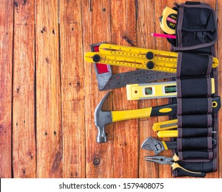 Construction Tools In Toolbelt On Wooden Background. Maintenance Concept. Top View