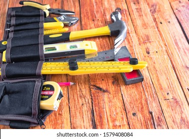 Construction Tools In Toolbelt On Wooden Background. Maintenance Concept.