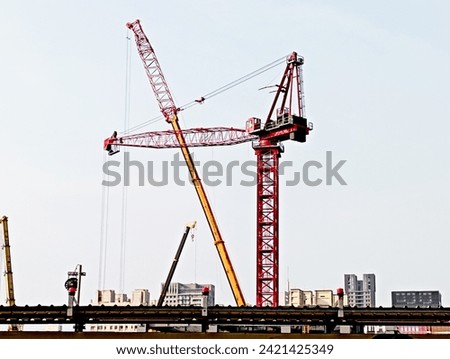 Construction tower crane at construction site is being modified to increase length and height. Of consistent importance are safety systems such as slings, masts, limit switches, jibs and derricks.
