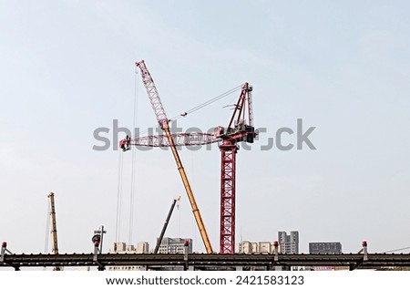 Construction tower crane at construction site is being modified to increase length and height. Of consistent importance are safety systems such as slings, masts, limit switches, jibs and derricks.