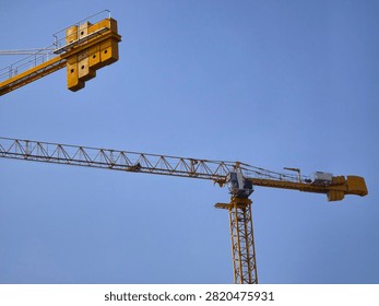 Construction Tower Crane with Two Extended Arms against a Clear Blue Sky