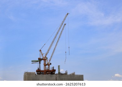 construction tower crane work with construction worker on top of building, used in construction site with blue sky.