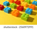 Construction toy. Colorful building bricks on yellow background, closeup