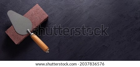 Construction trowel tool at brick on black background. Mason and bricks