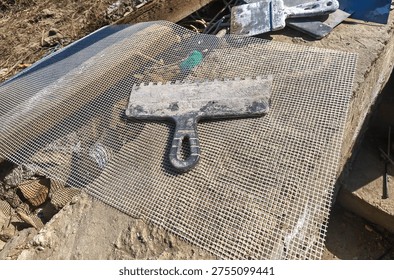 Construction trowel and tools on mesh with mortar during exterio