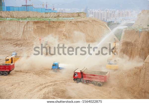The construction truck works on the\
construction site. The background is the city\
