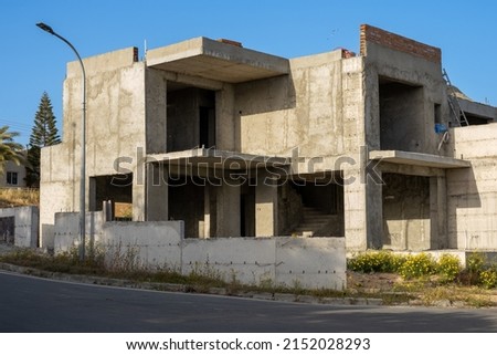 Construction of a two-story private house of concrete and brick. House under construction on the street. An unfinished building abandoned due to lack of money.