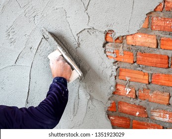 Construction under building with mason plastering concrete to brick wall