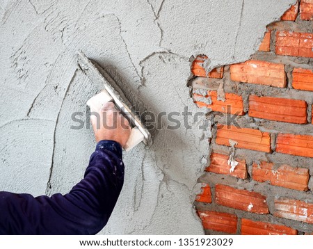 Construction under building with mason plastering concrete to brick wall