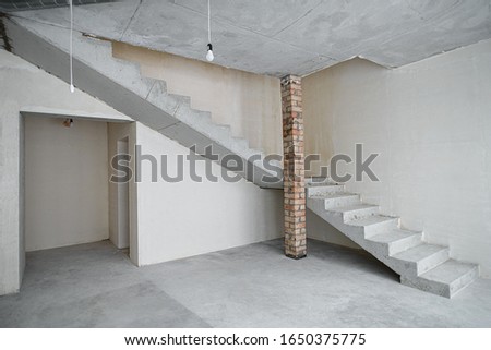 Construction. Unfinished building. Rough finish of the room. A large empty room with plastered walls in a house under construction. Concrete walls. Interior renovation.