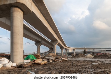 Construction of an urban multi-level road junction. Concrete overpass on high supports. The process of building roads and bridges. Building materials, debris and dirt. Bottom view