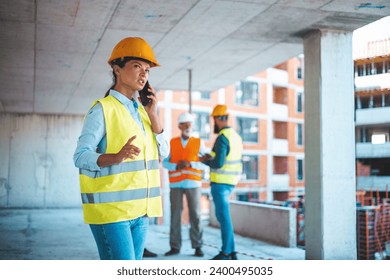 Construction woman closing deal on the phone. Portrait of civil engineer woman doing business, talking on smartphone and holding tablet computer in hand, standing against high buildings - Powered by Shutterstock