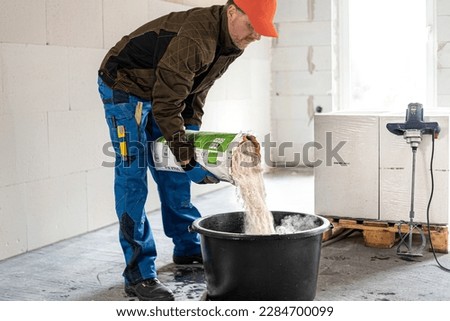 Construction work. Adding dry mortar mixture into clear water to make a mortar.