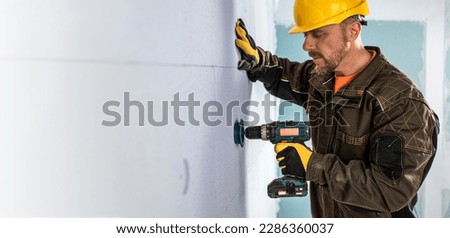 Construction work banner. The worker using aku screwdriver for preparing hole to the mineral insulation board for insulation fastener.
