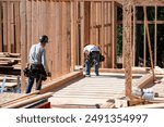 Construction work crew building a new house in a residential neighborhood, wood framing started, sunny summer construction season
