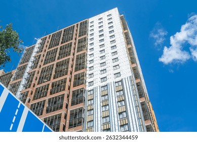 Construction work on the exterior cladding. Laying waterproofing material on the walls of a high-rise building. Insulation of the house. Balconies of a house under construction.
