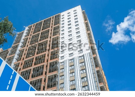 Construction work on the exterior cladding. Laying waterproofing material on the walls of a high-rise building. Insulation of the house. Balconies of a house under construction.