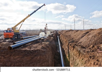 Construction work on the pipe laying of the pipeline into the trench using a crane