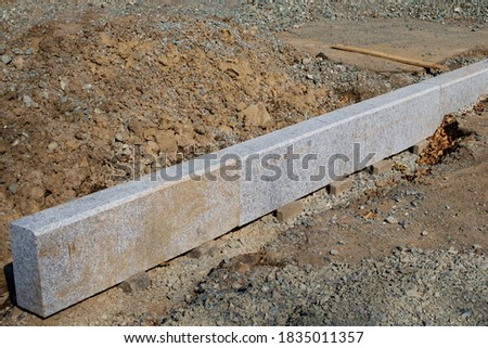 Construction work. Road curb made of granite slabs installed on a prepared drainage ditch. Selective focus.