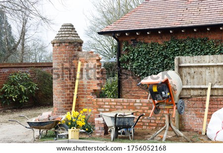Construction work with tools and cement mixer, building a brick garden wall outside a UK house