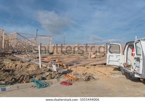 Construction work van with door open\
in the back and working tools inside near construction site. Wood\
frame house project foundation framing in Irving, Texas,\
USA.